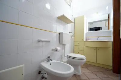 a white bathroom with a toilet and a sink at Villa Stella Cinese in Alcamo