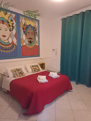 a bedroom with a red bed with a painting on the wall at Casuzza Ballarò in Palermo