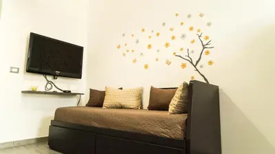 a bedroom with a couch with a tree on the wall at Il Nido del Gabbiano in Bagheria