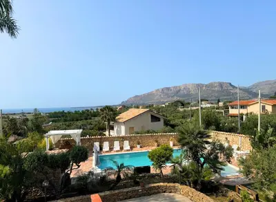a resort with a swimming pool and mountains in the background at Case Vacanza Zeus in Trappeto