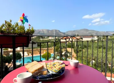 a pink table with a plate of bread and two cups at Case Vacanza Zeus in Trappeto