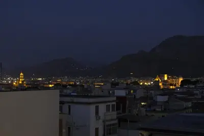 a view of a city at night with mountains at THE VIEW in Palermo