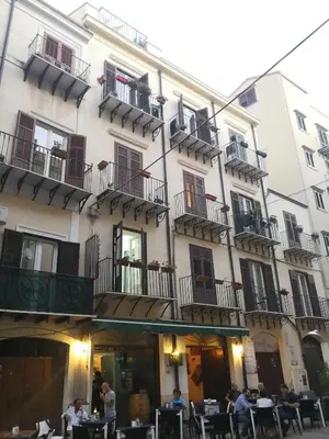 a building with people sitting at tables in front of it at Cassàri Suite in Palermo