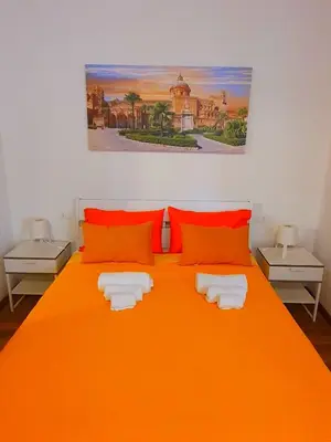 a bedroom with an orange bed with orange pillows at Normanni Homes in Palermo