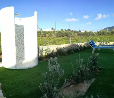 a lawn with a blue chair in a yard at Spacious villa with sea and mountain views in Alcamo in Alcamo