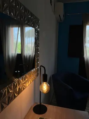 a room with a mirror and a lamp and a chair at Xenia House in Lascari