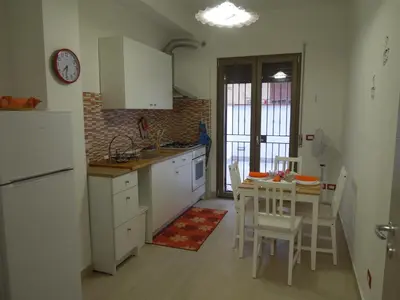 a kitchen with white cabinets and a table and chairs at Mondello Rose House in Palermo