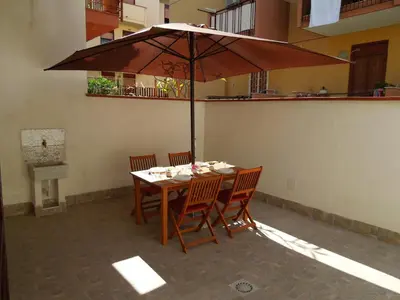 a wooden table with chairs and an umbrella at Mondello Rose House in Palermo
