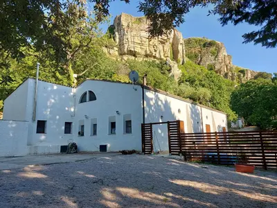 a white building with a fence and a mountain at Chiosi Country Club in Corleone