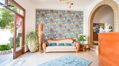 a living room with a couch and a floral wall at Agave Superior Rooms in San Vito lo Capo