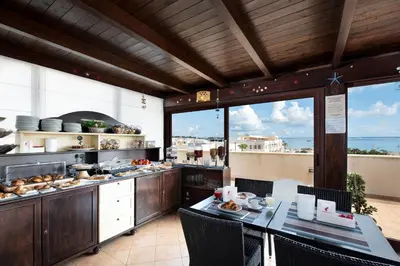 a kitchen with a table and chairs in a restaurant at Hotel Baia Di Venere in San Vito lo Capo