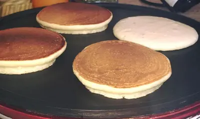 four pancakes on a black plate on a table at Hotel Baia Di Venere in San Vito lo Capo