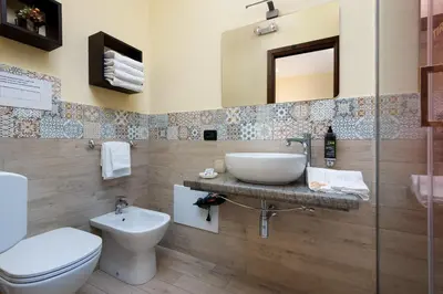 a bathroom with a sink and a toilet and a mirror at Hotel Baia Di Venere in San Vito lo Capo