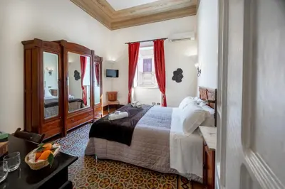 a bedroom with a bed and a dresser and a mirror at B&B Novecento in Palermo