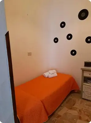 a bedroom with an orange bed with black records on the wall at Casa Mimì in Castellammare del Golfo