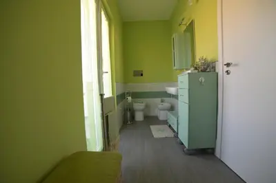 a green bathroom with a toilet and a sink at STANZINA DELLA BARONESSA in Carini