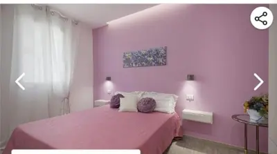 a pink bedroom with a bed with purple walls at Appartamento solare in Castellammare del Golfo