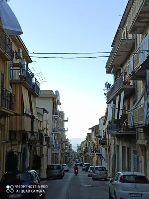 a motorcycle driving down a city street with buildings at Appartamento solare in Castellammare del Golfo