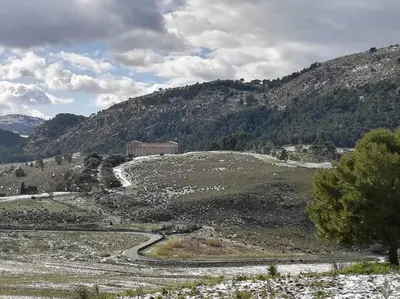 a winding road in a field with a mountain at Piccolo Sole d'oro - appartamenti in Calatafimi