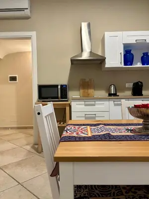 a kitchen with white cabinets and a wooden table at Palermo Centre - Apartments with Private Balcony or Terrace in Palermo