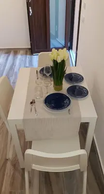 a white table with two plates and a vase of flowers on it at Casa Margò in Monreale