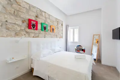 a bedroom with a white bed and a stone wall at Stabile Central Studios in Palermo