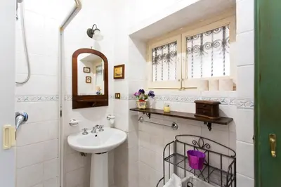 a white bathroom with a sink and a mirror at Maison Tulip in Palermo