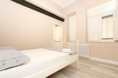 a white bedroom with a bed and two windows at Le case d'un tempo in Palermo