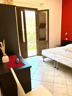 a room with a bed and a table and a door at Bed And Breakfast Turi in Castelluzzo