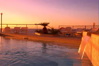 a pool with chairs and tables on a pier with the ocean at Bellevue del Golfo Hotel & Spa in Sferracavallo