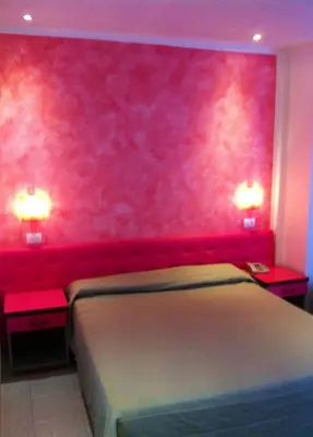 a bedroom with a pink wall with a bed and two tables at Bellevue del Golfo Hotel & Spa in Sferracavallo