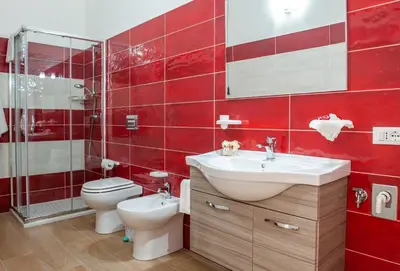 a red tiled bathroom with a toilet and a sink at Da Ida e Gianni in Castellammare del Golfo