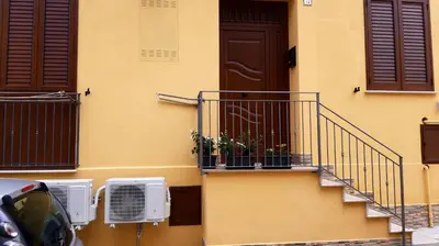a building with a door and a balcony with a plant on it at Da Ida e Gianni in Castellammare del Golfo