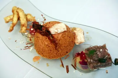 a plate of food on a glass plate with french fries at Zingaro Hotel in San Vito lo Capo