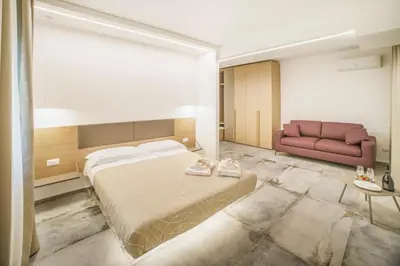 a bedroom with a large bed and a red couch at Oasi del Golfo Suites B&B in Castellammare del Golfo
