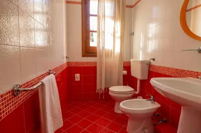 a red bathroom with a toilet and a sink at Casa Cavour sul Mare in San Vito lo Capo