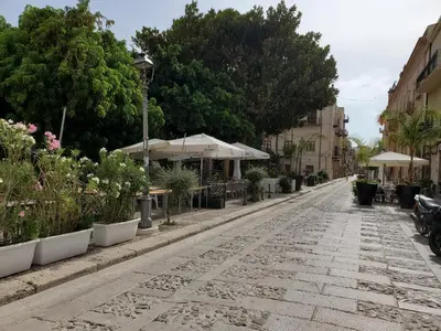 a cobblestone street with plants and umbrellas at Palazzo del Golfo Penthouse in Castellammare del Golfo