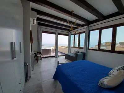 a bedroom with a blue bed and a view of the ocean at Palazzo del Golfo Penthouse in Castellammare del Golfo
