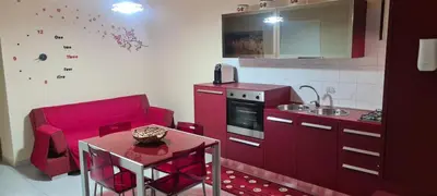 a kitchen with red cabinets and a small table and a kitchen at Giusy's Place 2.0 in Campofelice di Roccella