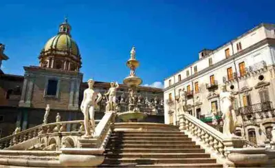 a building with a staircase in front of a building with a statue at H Urban in Palermo