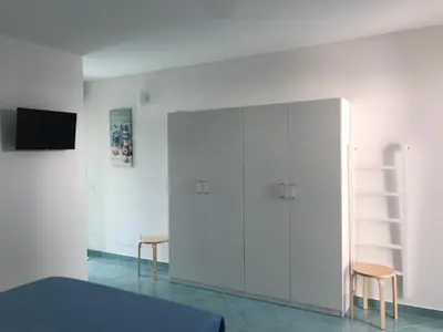 a bedroom with a large white closet and two stools at La casa di fronte la spiaggia di San Vito lo capo in San Vito lo Capo