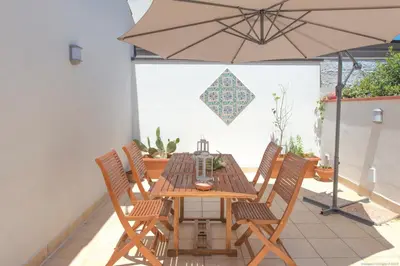 a wooden table with chairs and an umbrella on a patio at Casa Martini Mondello in Palermo