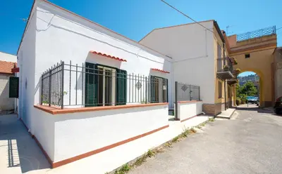 a white building with green doors and a balcony at Casa Martini Mondello in Palermo