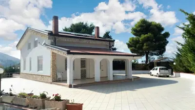 a white house with a car parked in the driveway at Charming Villa in Monreale with Private Pool in Pioppo