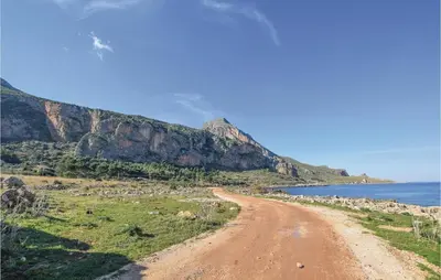 a dirt road next to the ocean with a mountain at Lovely Home In Makari-S Vito Lo Capo in Macari