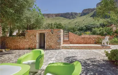 a patio with green chairs and a stone wall at Lovely Home In Makari-S Vito Lo Capo in Macari