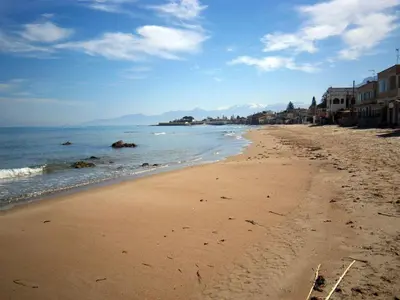 a sandy beach with buildings and the ocean at Terrazza sul mare in Trabia