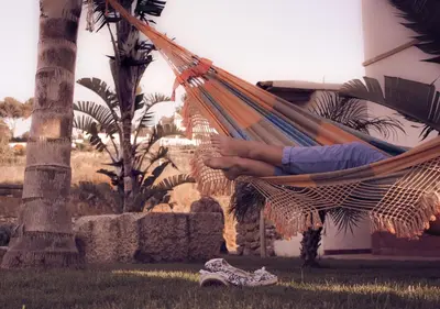 a person sitting in a hammock in at Giardini Del Golfo in Balestrate