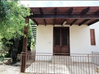 a small house with a wooden door and a fence at Il Volo Dei Gabbiani in Scopello