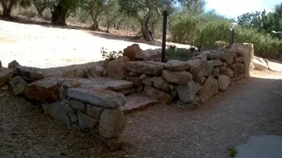 a stone wall with a bench in a park at Il Volo Dei Gabbiani in Scopello